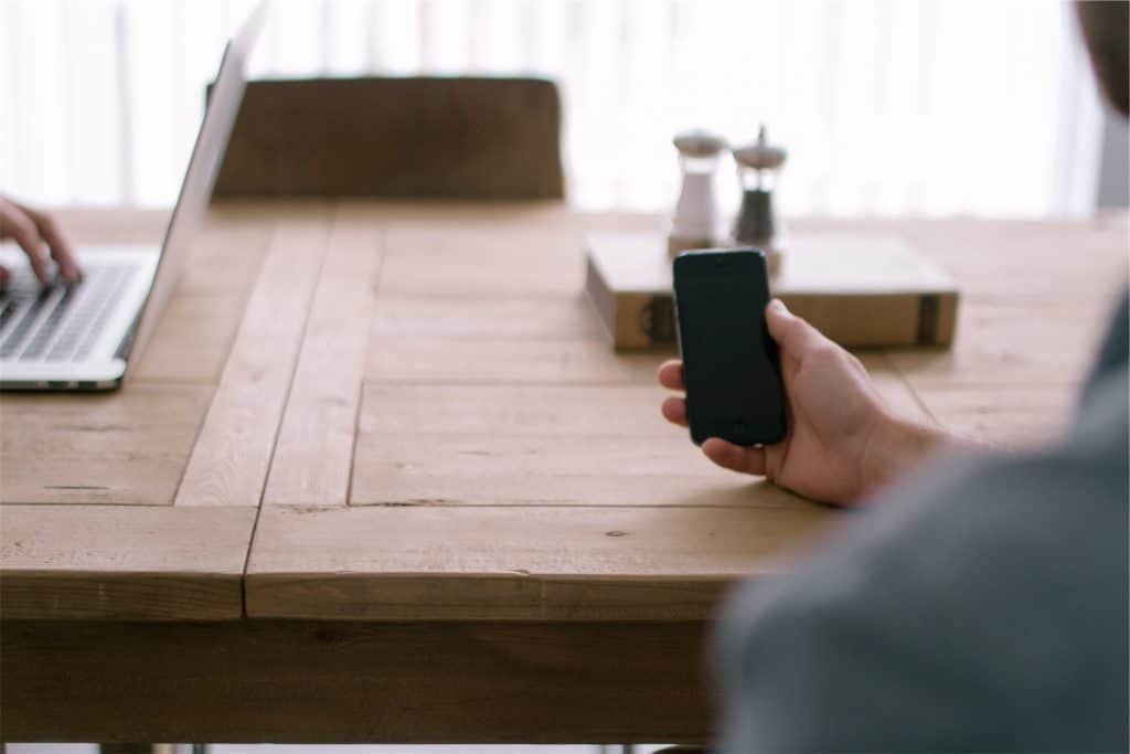 Photo of person holding a phone at a desk for contact page