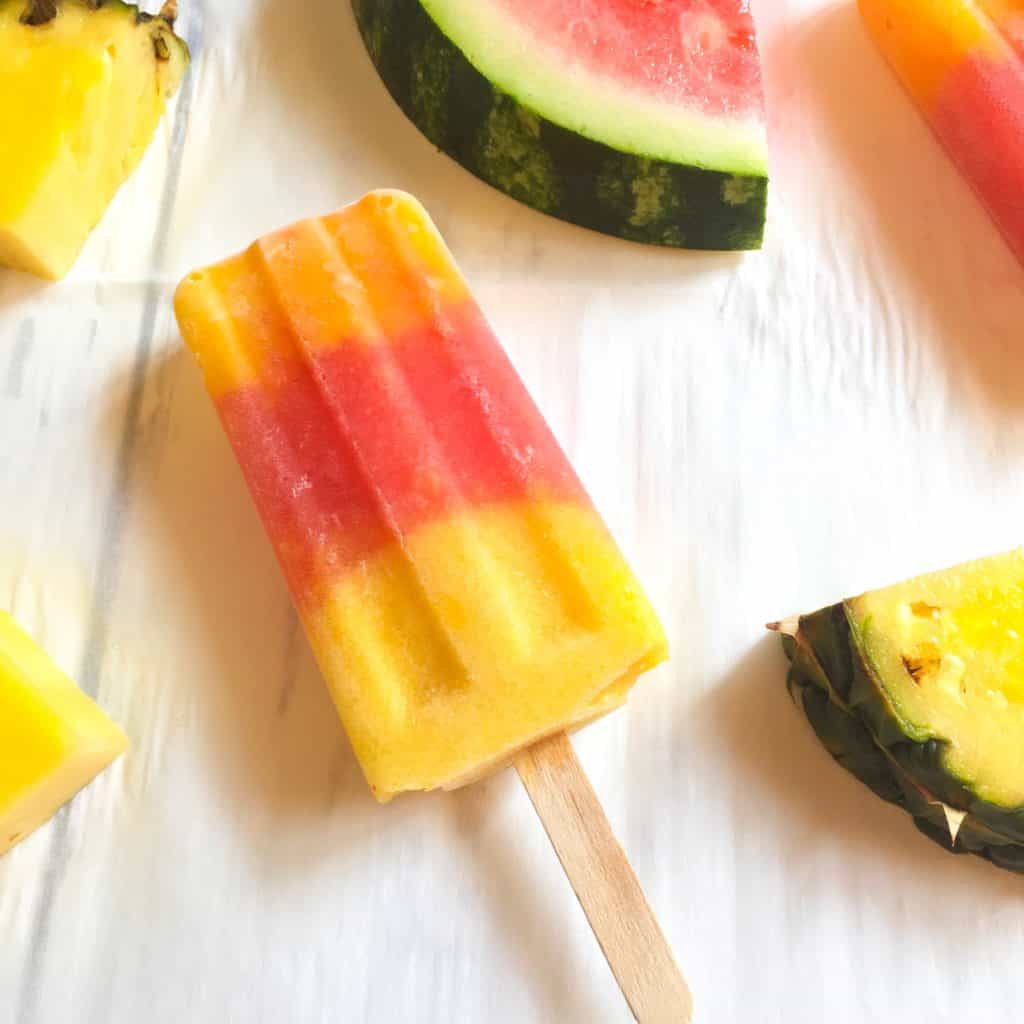 Mango Watermelon Pineapple Pop surrounded by pieces of cut watermelon and pineapple