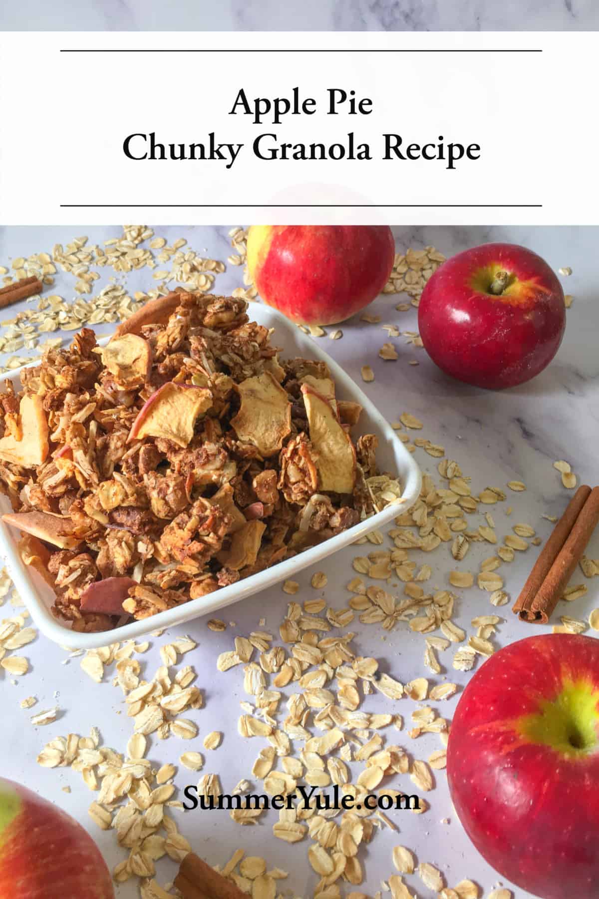 Bowl of the apple pie chunky granola recipe surrounded by apples, rolled oats, and cinnamon sticks