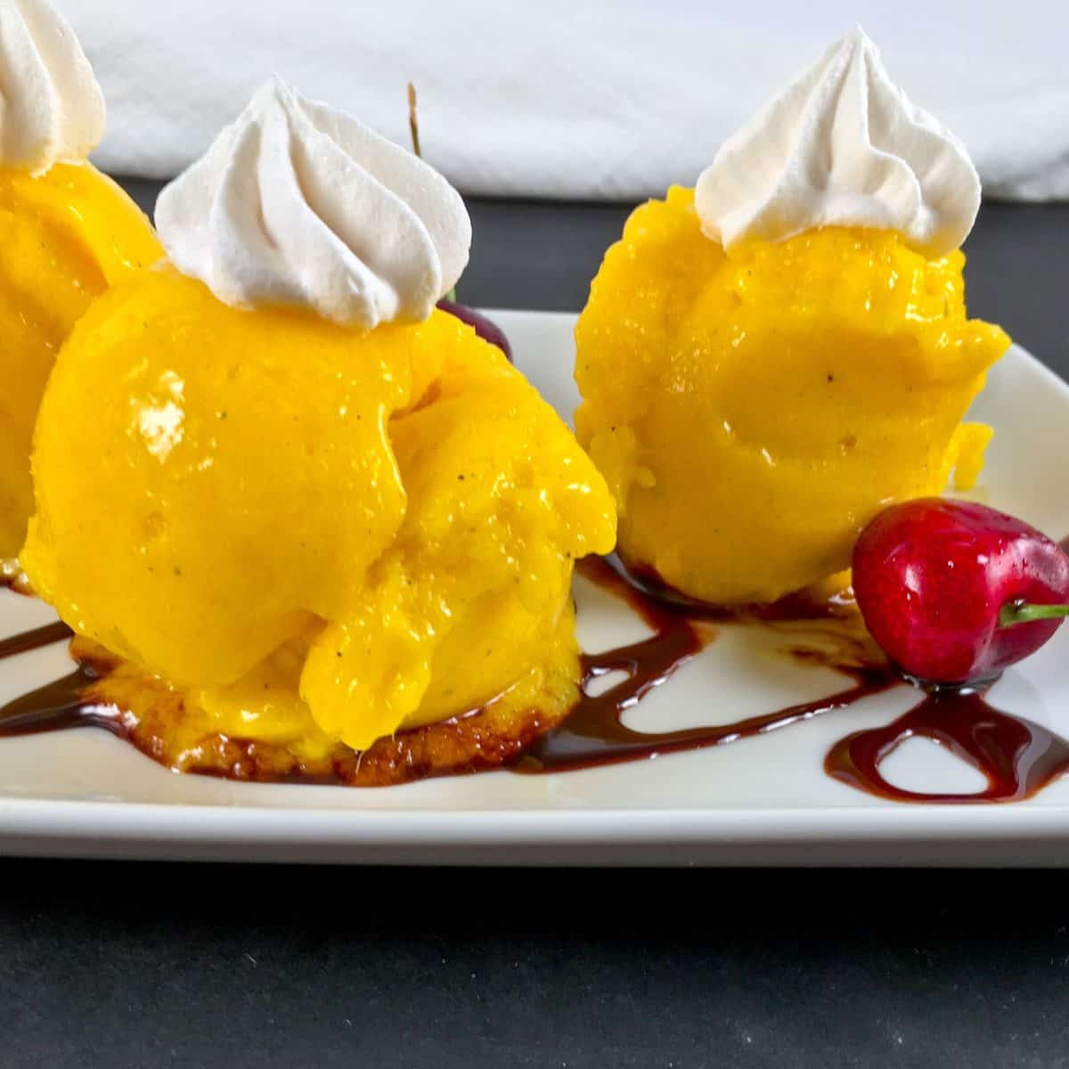 Melting mango nice cream with whipped cream and chocolate sauce